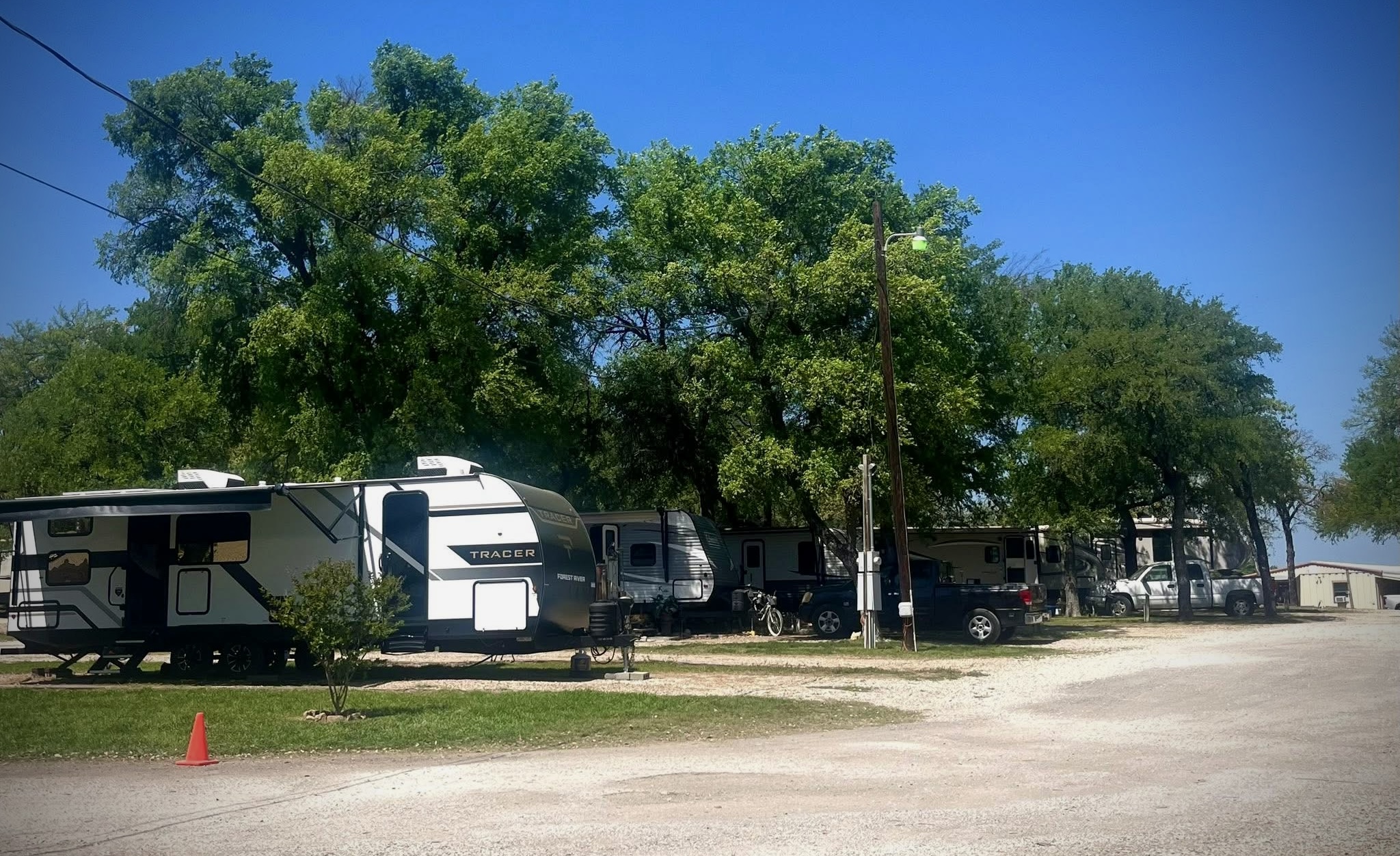 Travel trailers lined up along a tree-shaded lane at the ranch